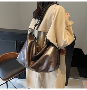 Détail du sac cabas marron foncé avec large bandoulière et pendentif ours sur un mannequin