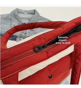 Close-up of smooth black metal zipper on a red canvas tote bag with white trim