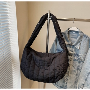 Detail of black quilted puffer bag showing wide strap with metal eyelet ornaments