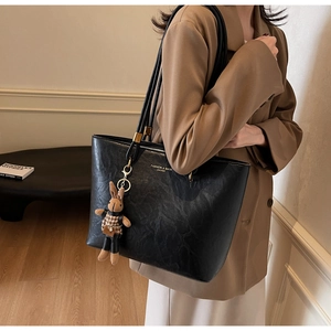 Détail d'un sac cabas en cuir noir avec un charm lapin en peluche pour le quotidien