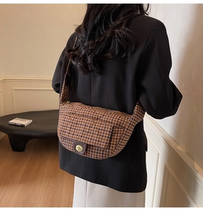Detail of vintage houndstooth crossbody bag with brown leather flap and gold twist lock