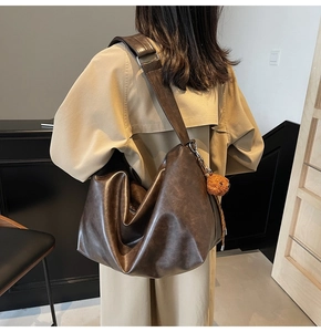 Vue détaillée du sac hobo marron avec large bandoulière et pendentif ours