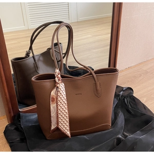 Close-up of brown litchi pattern leather tote bag with decorative silk scarf and logo