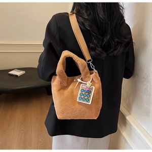 Detail of brown fuzzy plush bucket bag with wide strap and cartoon calculator charm