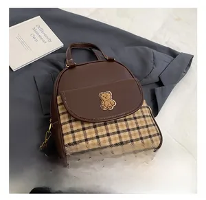 Close-up of vintage brown leather backpack featuring a classic plaid base and bear patch