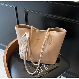 Detail of light brown tote bag with pebble leather texture and silk scarf decoration