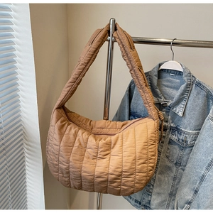 Detail view of khaki quilted tote bag with wide strap hanging on a metal hanger
