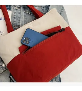 Detail of red and white nylon tote bag showing front zipper pocket for smartphone storage