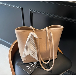 Close-up of beige leather tote bag with lychee texture and silk scarf handle detail