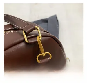 Detail of premium brown leather backpack with golden metal hooks and contrast stitching