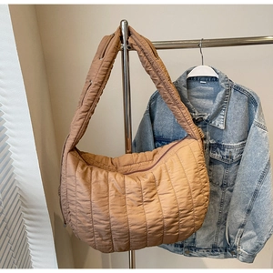Detailed close-up of quilted stripe puffer shoulder bag with drawstring adjustable strap