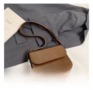 Detail of a dark brown square crossbody bag with smooth leather finish and fine stitching
