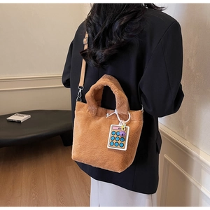 Detailed back view of a brown plush bucket bag with a calculator charm and nylon strap