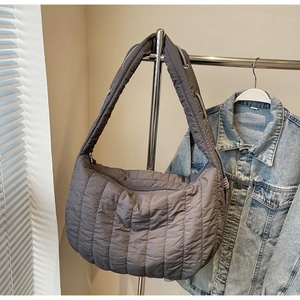 Close-up of quilted grey down fabric tote bag hanging with casual denim jacket