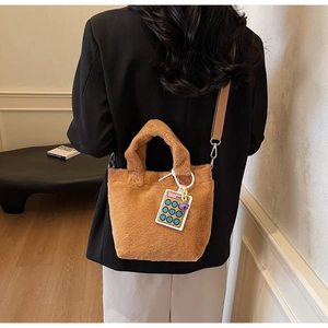 Detail of brown plush bucket bag with cute calculator charm and wide strap on model