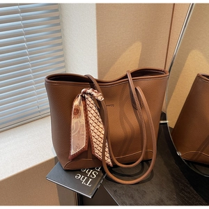 Close-up of dark brown lychee leather tote bag with printed silk scarf detail