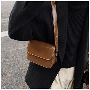 Brown leather crossbody square bag styled with a black wool blazer and white pants