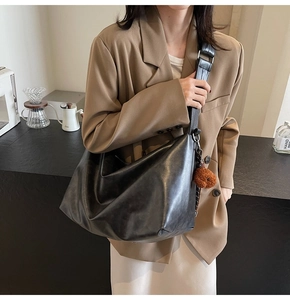 Détail du sac cabas en cuir mat noir avec large bandoulière et charm ours en peluche