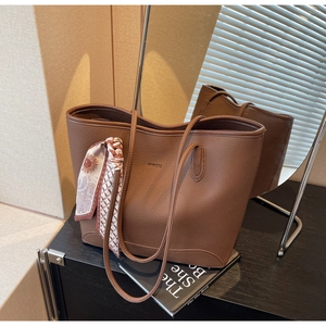 Close-up of brown litchi grain tote bag with decorative floral scarf and logo detail