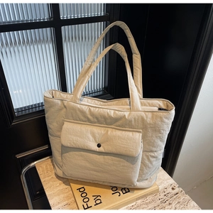 Detail of beige quilted tote bag showing zipper closure and textured puffer material