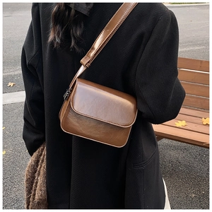 Detail of vintage dark brown glossy leather crossbody bag with adjustable shoulder strap