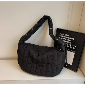 Detail of black quilted puffer tote bag showing metallic eyelets and adjustable strap