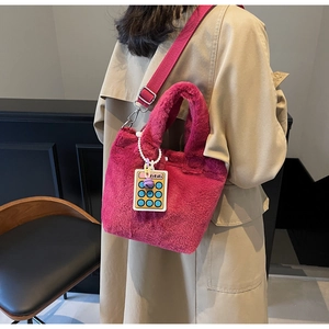 Detail of rose red plush bucket bag with fluffy texture and cute calculator pendant