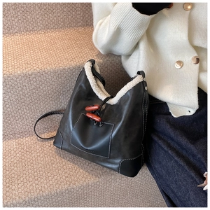 Detailaufnahme der schwarzen Ledertasche mit weißem Pelzbesatz und Retro-Knebelknöpfen