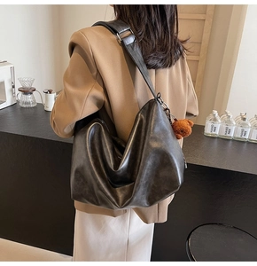 Détail du sac hobo rétro noir avec bandoulière large et breloque ours brun sur le côté
