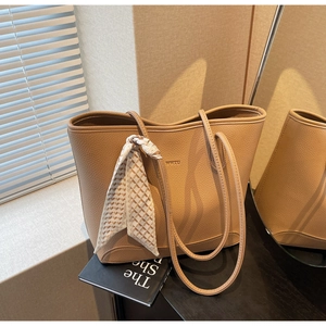 Close-up of camel tote bag in lychee leather texture with a decorative silk scarf