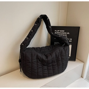 Detail view of black pleated tote bag showing waterproof fabric and silver eyelet accents