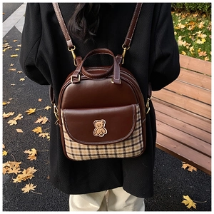 Detail of vintage mini backpack with plaid fabric and cute bear patch in autumn outdoor setting