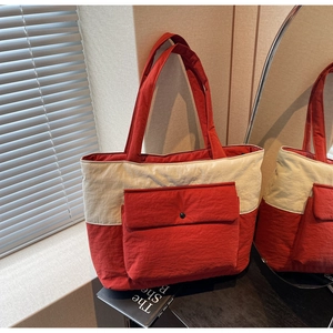 Detail of red and white canvas tote bag with front pocket and snap button closure