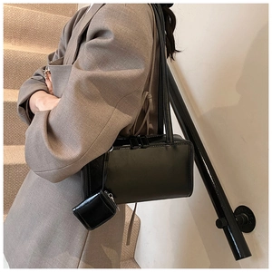 Detail of black glossy faux leather shoulder bag with matching mini square pouch charm