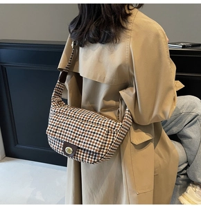 Detail view of houndstooth plaid pattern and golden metal lock on a half-moon bag