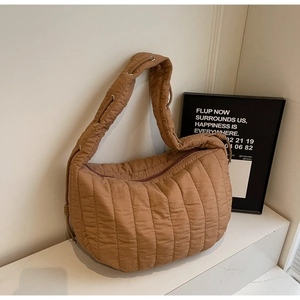 Close-up of caramel brown quilted tote bag showing soft vertical stitching and wide strap