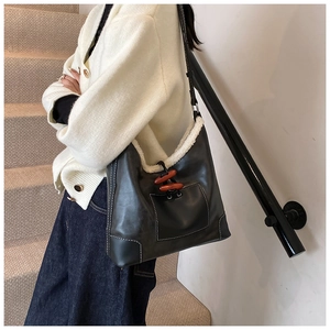 Detail der schwarzen Ledertasche mit weißem Lammfellbesatz und hölzernen Knebelknöpfen