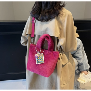 Fuchsia faux fur bucket bag shown worn with a khaki coat and adjustable strap
