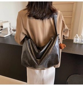 Détail d'un grand sac hobo noir avec un porte-clés en peluche d'ours brun