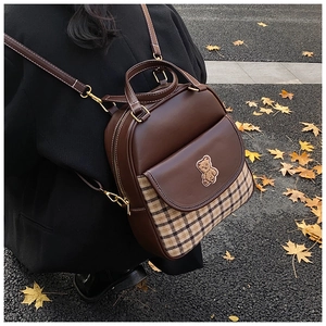 Detail shot of vintage plaid leather backpack with bear embroidery on autumn street