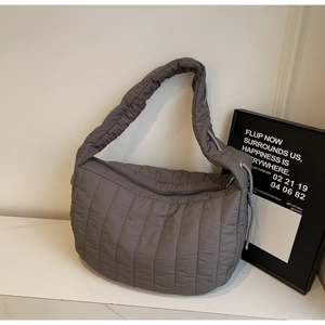 Close-up of grey quilted tote bag with vertical stitching and wide shoulder strap