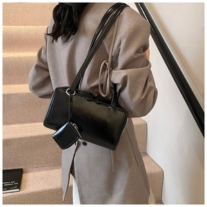 Detail of black glossy patent leather shoulder bag with a small square pouch accessory