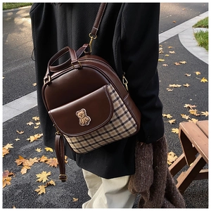 Outdoor shot of stylish plaid patchwork backpack with cute bear embroidery detail