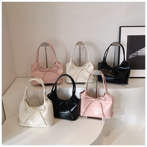 Petits sacs à main minimalistes en rose, blanc et noir présentés sur un présentoir