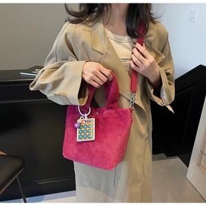 Detail of plush fuchsia crossbody bag with fabric strap and calculator charm
