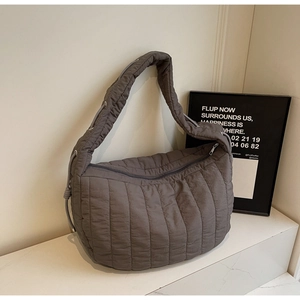 Detail of grey quilted tote bag featuring padded wide straps and ruched fabric texture