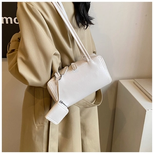 Detail of white PU leather baguette bag with mini charm pouch shown on shoulder