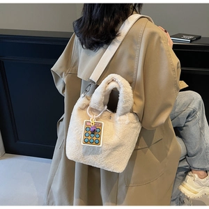 Detail of plush bucket bag in cream white with wide strap and calculator charm