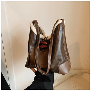 Detail einer braunen Vintage-Tasche mit Kunstlammfellbesatz und dekorativem Hornknopf