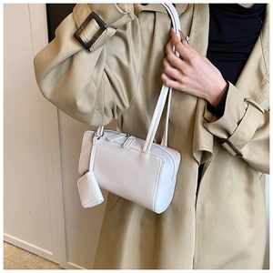 Detailed shot of white faux leather pillow bag with mini pouch on a model shoulder